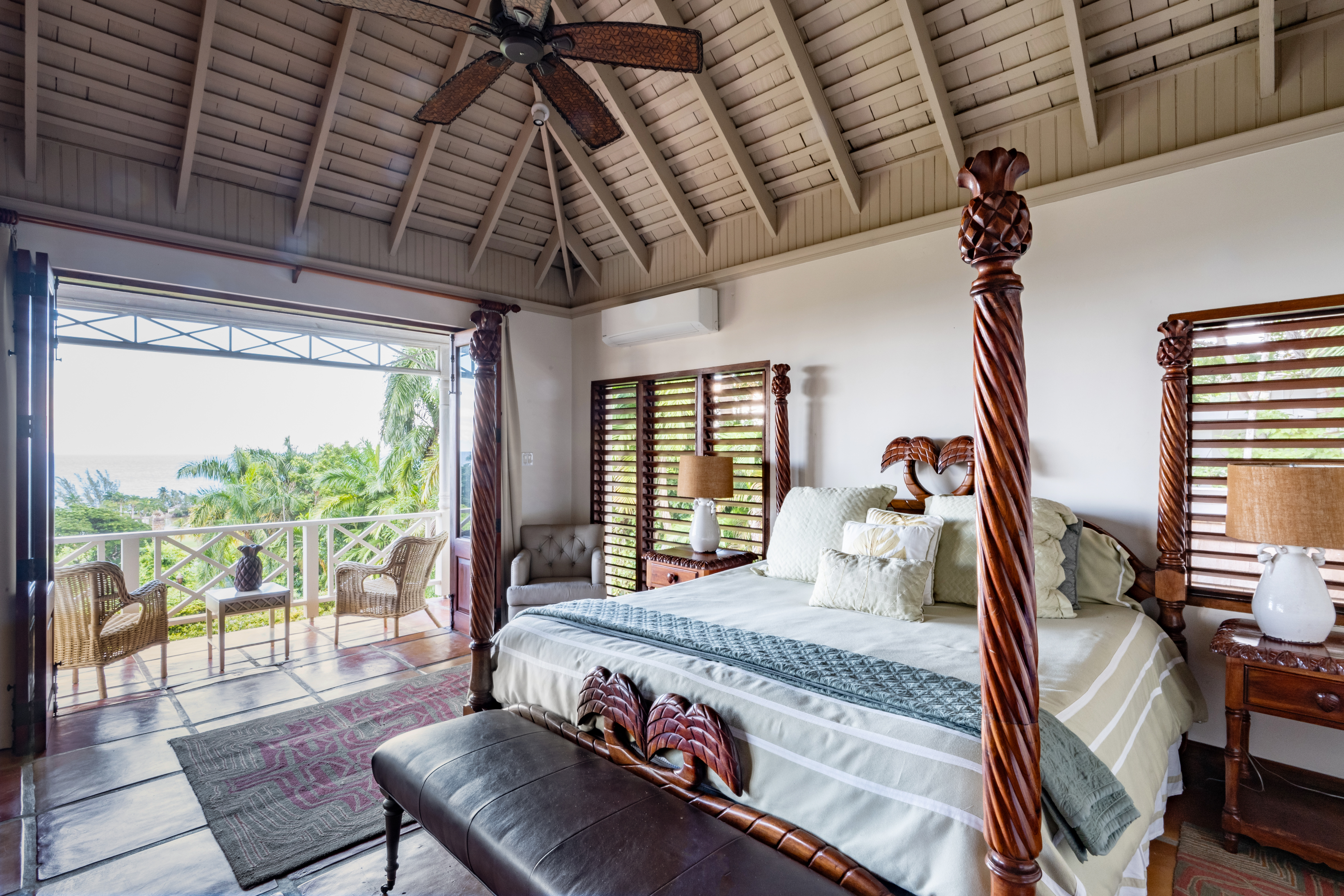 Pineapple House bedroom with a large bed and chairs on the balcony