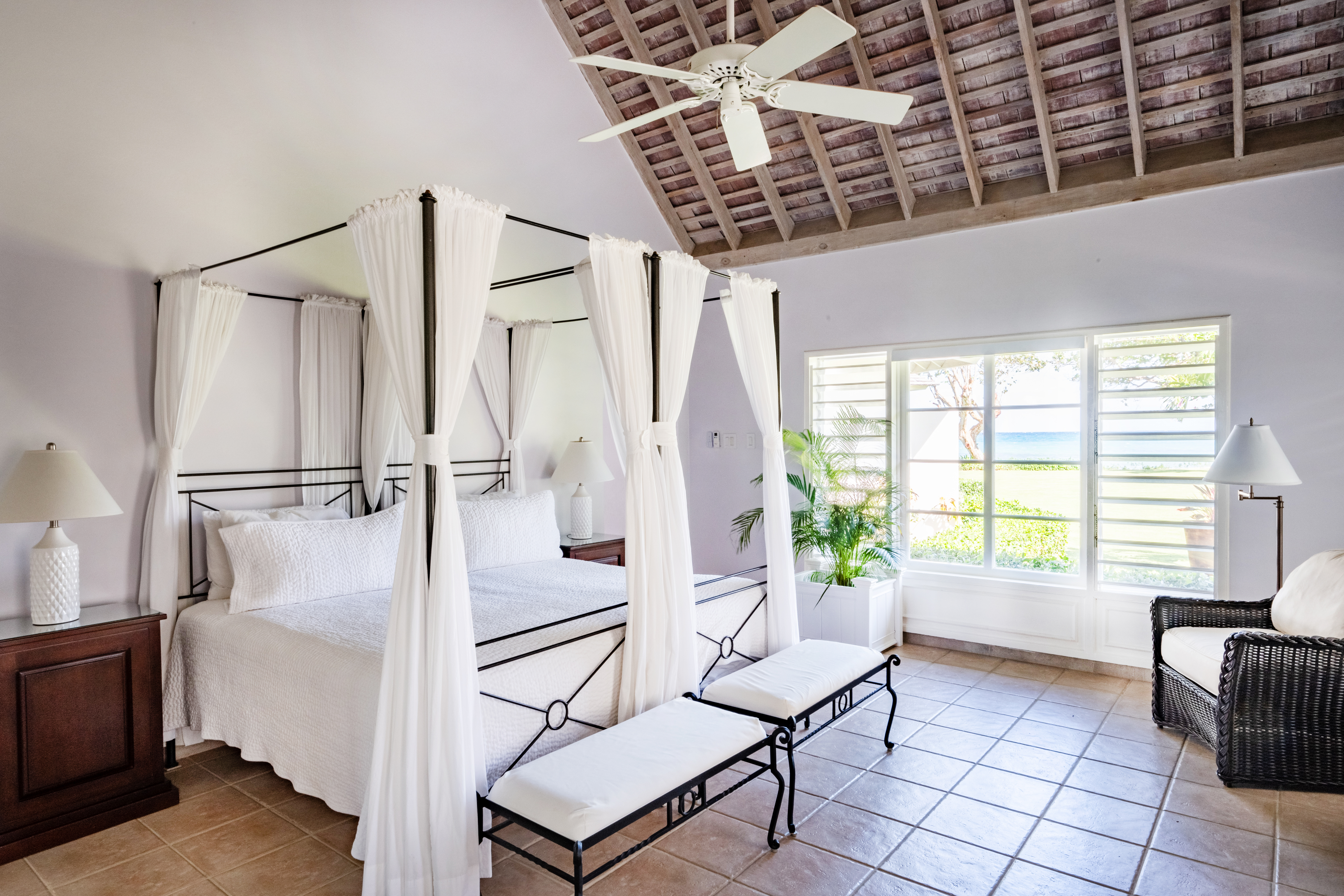 Phoenix villa bedroom with a large bed, foot stool and fan